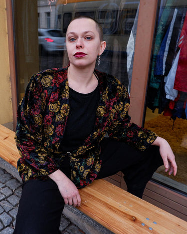 Add a touch of vintage glamour to your wardrobe with our 80s inspired velvet blazer. The delicate floral pattern features a subtle shimmer, adding a touch of luxury to this thin jacket. Perfect for a playful yet sophisticated look. Please keep in mind that the shimmering outerline of the flowers feels a bit scratchy.