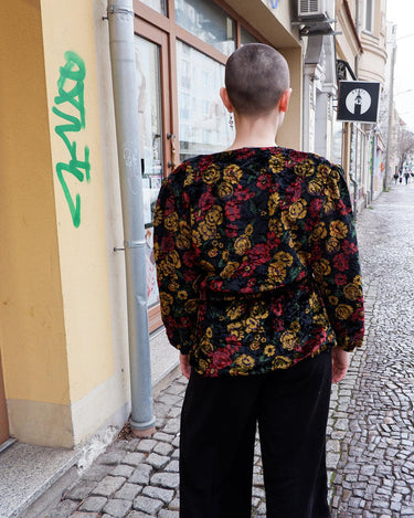 Add a touch of vintage glamour to your wardrobe with our 80s inspired velvet blazer. The delicate floral pattern features a subtle shimmer, adding a touch of luxury to this thin jacket. Perfect for a playful yet sophisticated look. Please keep in mind that the shimmering outerline of the flowers feels a bit scratchy.