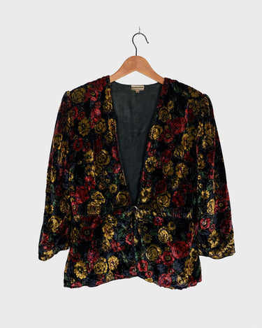 Add a touch of vintage glamour to your wardrobe with our 80s inspired velvet blazer. The delicate floral pattern features a subtle shimmer, adding a touch of luxury to this thin jacket. Perfect for a playful yet sophisticated look. Please keep in mind that the shimmering outerline of the flowers feels a bit scratchy.