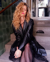 Introducing our Vintage 90s black long leather button coat! Timeless, sleek, and classic, this coat is the perfect addition to any wardrobe. Featuring a button closure, it exudes elegance.