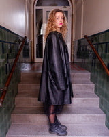 Introducing our Vintage 90s black long leather button coat! Timeless, sleek, and classic, this coat is the perfect addition to any wardrobe. Featuring a button closure, it exudes elegance.