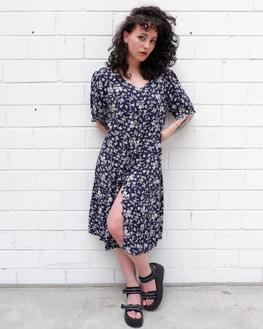 Dress to impress in this vintage 90s blue midi dress with a floral pattern! Tie it tighter for an S-M fit or let it go for a L-XL! Get yours now and get dressed to express!