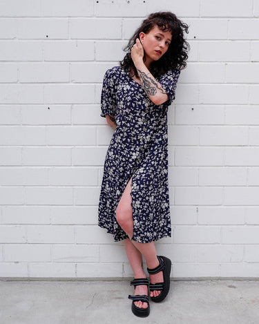 Dress to impress in this vintage 90s blue midi dress with a floral pattern! Tie it tighter for an S-M fit or let it go for a L-XL! Get yours now and get dressed to express!