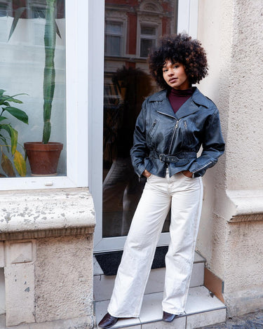 Unleash your inner badass with this Vintage 80s black biker leather jacket. The edgy look is complete with a belted waist and light shoulder pads, making it the perfect statement piece for spring. Crafted from light leather, it provides style and comfort.