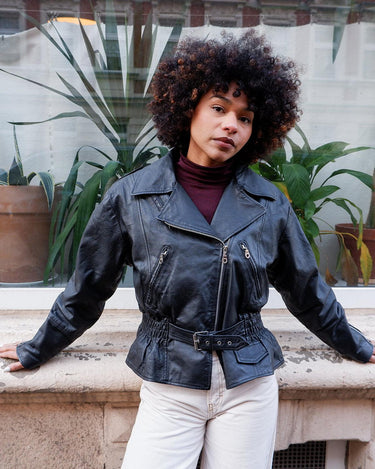 Unleash your inner badass with this Vintage 80s black biker leather jacket. The edgy look is complete with a belted waist and light shoulder pads, making it the perfect statement piece for spring. Crafted from light leather, it provides style and comfort.