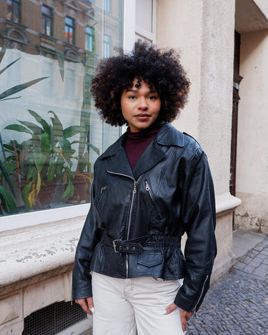 Unleash your inner badass with this Vintage 80s black biker leather jacket. The edgy look is complete with a belted waist and light shoulder pads, making it the perfect statement piece for spring. Crafted from light leather, it provides style and comfort.