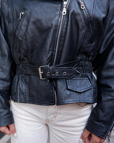 Unleash your inner badass with this Vintage 80s black biker leather jacket. The edgy look is complete with a belted waist and light shoulder pads, making it the perfect statement piece for spring. Crafted from light leather, it provides style and comfort.