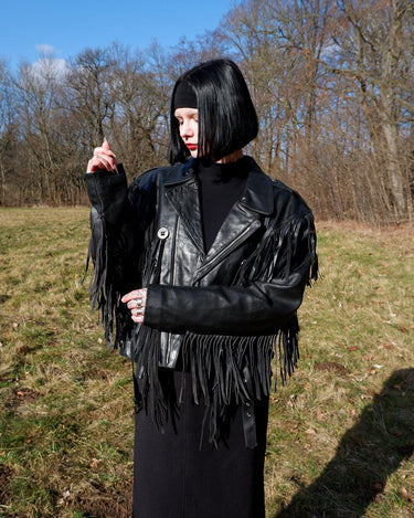 Add some wild vibes to your wardrobe with this vintage 80s 90s black fringe leather jacket. Complete with conchos and a belt, this jacket will be a statement piece for any outfit.
