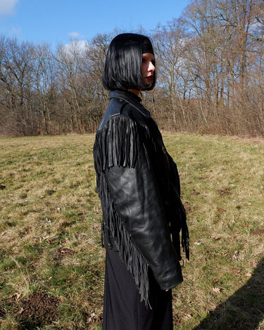 Add some wild vibes to your wardrobe with this vintage 80s 90s black fringe leather jacket. Complete with conchos and a belt, this jacket will be a statement piece for any outfit.