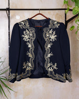 Embrace this Vintage 80s Spring Blazer! Featuring golden stitches and shoulder pads, this blazer (no closure) is definitely a statement piece. The floral and geometric pattern adds an extra touch of playfulness to any outfit. 