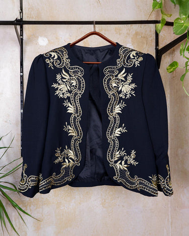 Embrace this Vintage 80s Spring Blazer! Featuring golden stitches and shoulder pads, this blazer (no closure) is definitely a statement piece. The floral and geometric pattern adds an extra touch of playfulness to any outfit. 