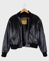 This iconic Vintage 80s black bomber leather jacket brings the edge with a serious dose of attitude! Boasting shoulder pads and a classic bomber jacket silhouette, it's sure to unleash your inner wild child!