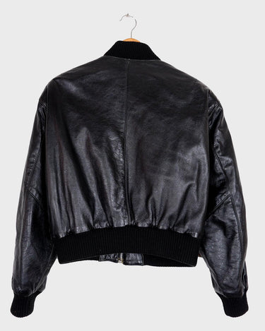 This iconic Vintage 80s black bomber leather jacket brings the edge with a serious dose of attitude! Boasting shoulder pads and a classic bomber jacket silhouette, it's sure to unleash your inner wild child!