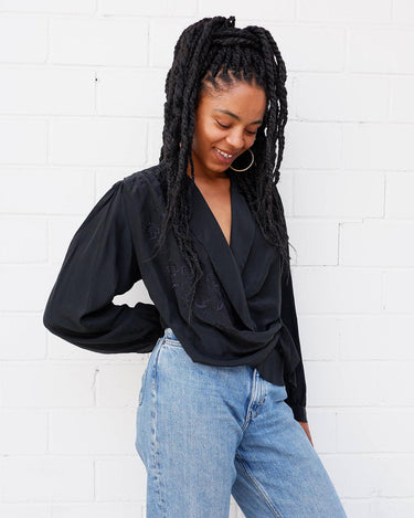 This classic vintage 90s black blouse has got you covered - literally! Wrap yourself up in this silky-smooth garment complete with shoulder pads and a fun floral pattern.