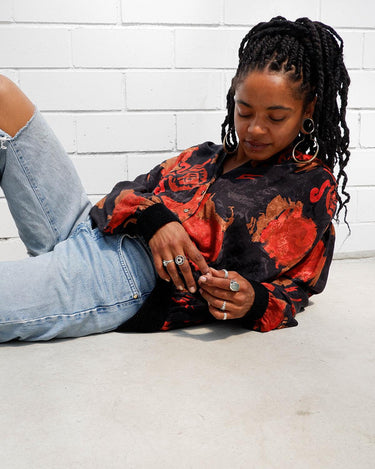This vintage 80s velvet x silk blouse is having a moment! Its flowy and lightweight transparent fabric, coupled with its stunning red floral pattern, make it a must-have!