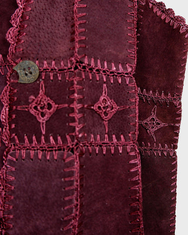 This burgundy leather vest is a vintage gem from the 80s, featuring unique stitching flowers and a boho-style cut. With no closure, it's perfect for layering over any outfit!