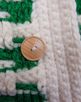 This handmade knit vest in rich green and cream tones is a true eye-catcher. Crafted from wool blend yarn and finished with natural wooden buttons, it blends cozy texture with bold design. The chunky crochet style and timeless check pattern make it perfect for layering.