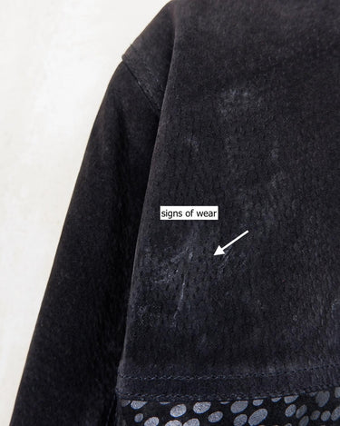 This vintage black leather coat blends matte suede leather with subtly glossy smooth leather panels in rich black tones. The unique patchwork design, featuring delicate dot-textured sections, adds depth, texture, and quiet individuality. With its sleek cut, button front, and spacious pockets, this timeless piece is full of character – perfect for those who appreciate quality and one-of-a-kind style.