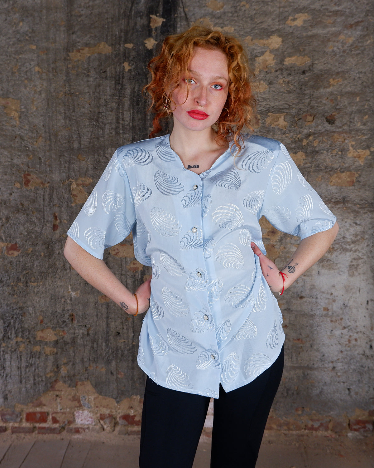 Introduce some sparkle to your style with this vintage 80s light blue blouse. The flattering fit, courtesy of the short sleeves and shoulder pads, meets a playful touch of shimmering pattern. Sparkle on!