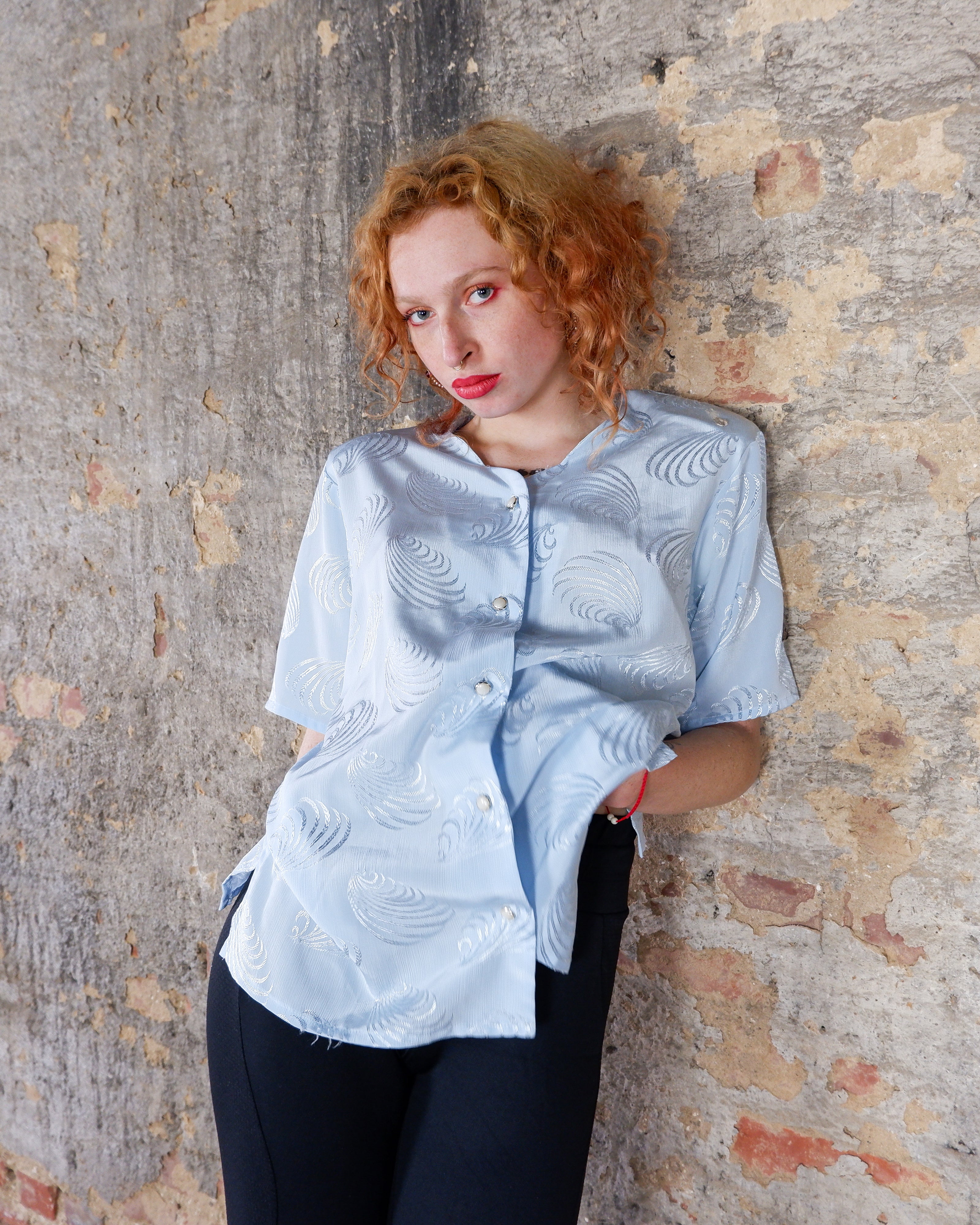 Introduce some sparkle to your style with this vintage 80s light blue blouse. The flattering fit, courtesy of the short sleeves and shoulder pads, meets a playful touch of shimmering pattern. Sparkle on!