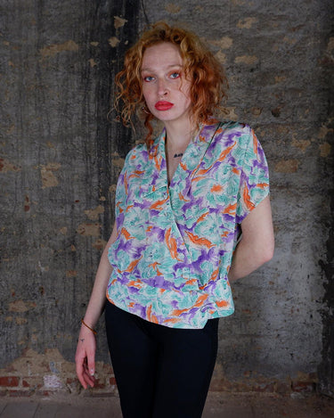 Add a pop of color to your wardrobe with this Vintage 80s colorful short sleeve blouse! Its diagonal button row adds a unique touch, and the lightweight fabric ensures comfort all day long. A fun and playful addition to any outfit.