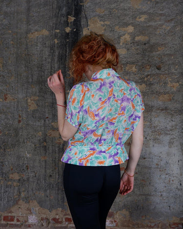 Add a pop of color to your wardrobe with this Vintage 80s colorful short sleeve blouse! Its diagonal button row adds a unique touch, and the lightweight fabric ensures comfort all day long. A fun and playful addition to any outfit.