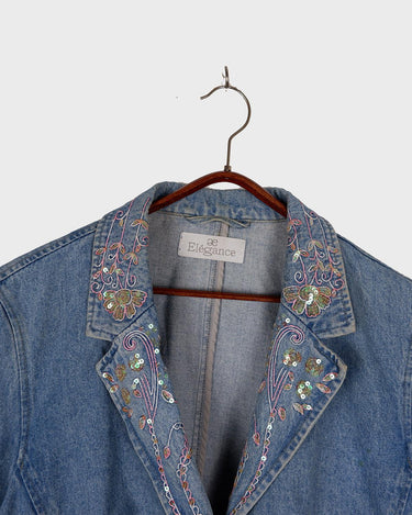 Add a touch of personality to your wardrobe with our Vintage 90s blue denim blazer. Featuring playful splashes of colorful pearls, this blazer exudes a fairy-like charm!
