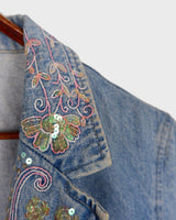 Add a touch of personality to your wardrobe with our Vintage 90s blue denim blazer. Featuring playful splashes of colorful pearls, this blazer exudes a fairy-like charm!