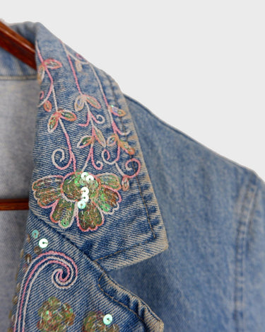 Add a touch of personality to your wardrobe with our Vintage 90s blue denim blazer. Featuring playful splashes of colorful pearls, this blazer exudes a fairy-like charm!