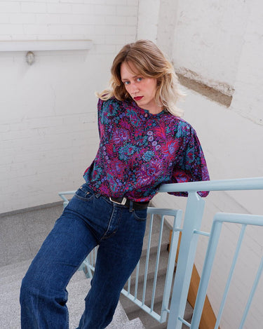Lookin' for a way to make some '80s style magic? Slip on this vintage purple floral blouse with light shimmering accents and shoulder pads for a look that sparkles!
