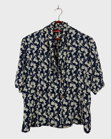 Get ready to channel some serious 90s romance with this vintage navy blue floral blouse with its light shimmering optic. Crafted from a luxurious silk mix blend, it features golden buttons and a unique collar for some extra flair. Romance never goes out of style!