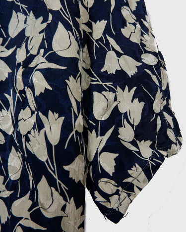 Get ready to channel some serious 90s romance with this vintage navy blue floral blouse with its light shimmering optic. Crafted from a luxurious silk mix blend, it features golden buttons and a unique collar for some extra flair. Romance never goes out of style!