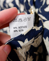 Get ready to channel some serious 90s romance with this vintage navy blue floral blouse with its light shimmering optic. Crafted from a luxurious silk mix blend, it features golden buttons and a unique collar for some extra flair. Romance never goes out of style!