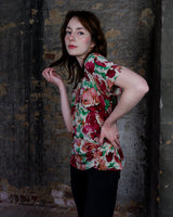 This vintage 1980s wrap blouse, crafted from luxurious pure silk, features a vibrant all-over rose print in rich red, pink, and green hues. The draped silhouette flows effortlessly, while a sculptural rose detail on the right side adds a bold, romantic twist. No tie needed – just slip it on and let the look speak for itself!