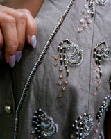 Fine beadwork and soft sequins give this 90s brown-grey waistcoat its understated shine – subtle, but impossible to miss. With a paisley satin back and belt, it’s a thoughtful piece for those who appreciate timeless style and fine detail.