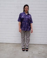 Bold, breezy, and silky smooth - this rare 90s short-sleeve gem by T. Corner is made from real Thai silk, brought to you by one of Thailand’s most renowned silk producers. The glossy fabric pops with a crazy pattern in electric purples and blues that’s impossible to ignore. Wear it loud, wear it proud!