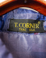Bold, breezy, and silky smooth - this rare 90s short-sleeve gem by T. Corner is made from real Thai silk, brought to you by one of Thailand’s most renowned silk producers. The glossy fabric pops with a crazy pattern in electric purples and blues that’s impossible to ignore. Wear it loud, wear it proud