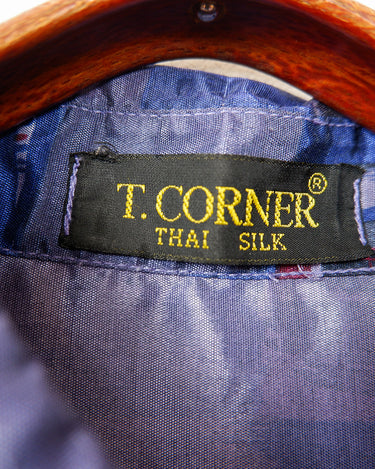 Bold, breezy, and silky smooth - this rare 90s short-sleeve gem by T. Corner is made from real Thai silk, brought to you by one of Thailand’s most renowned silk producers. The glossy fabric pops with a crazy pattern in electric purples and blues that’s impossible to ignore. Wear it loud, wear it proud