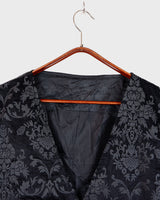 This Y2k black vest blends classic baroque style with a subtle gothic edge. The textured floral pattern and fleur-de-lis buttons give it a refined yet bold character. Cool, confident and a little unexpected – a standout piece without shouting.