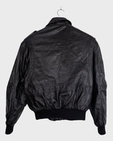 This vintage 90s black bomber jacket is a unisex must-have for any wardrobe! Made from heavy leather, this jacket boasts a timeless look with a touch of edge.
