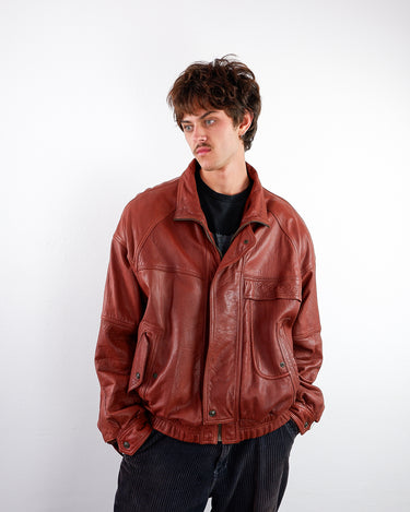 a man is wearing a Vintage 80s red brown bomber leather jacket with shoulder pads | L-XL from the online shop vinti vintage