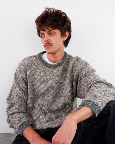 a man is wearing a Vintage 80s textured geometric knit sweater in grey with subtle color flecks | L-XL from the online shop www.vintivintage.com