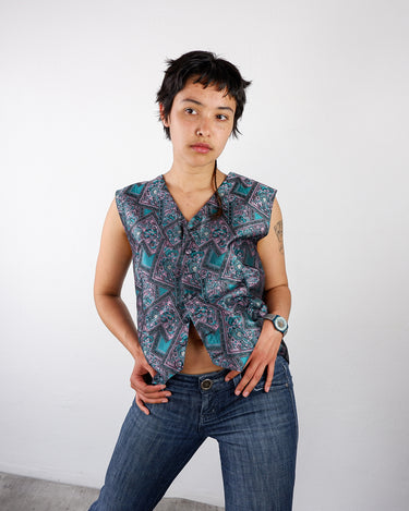 a woman is weariang a colorful vintage vest with geometric pattern in teal and pink by vinti vintage.