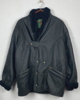 Experience timeless style with this Vintage 80s black faux leather shearling coat, featuring a warm lining that will keep you cozy. Just a heads up, the sleeves are not lined for extra warmth.
