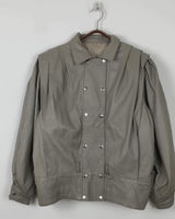 This Vintage 80s grey two row button leather jacket (thin material so perfect for spring) with its light brown undertone is a true timeless piece. From the two row button design to the leather material, this jacket is the perfect piece to embrace the classic look.