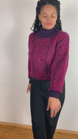 a woman is wearing a 80s dark pink geometric turtleneck sweater.