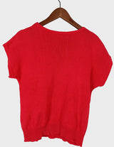 a woman is wearing a vintage 70s 80s red slipover.