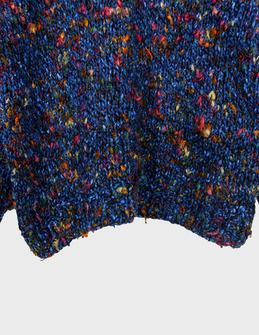 a woman is wearing a handknitted sweater.