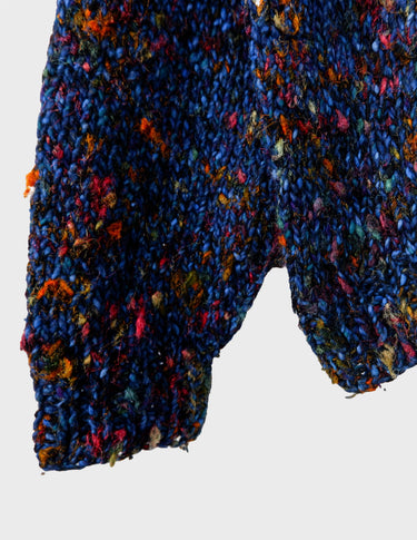 a woman is wearing a handknitted sweater.
