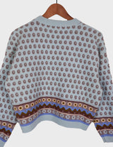a woman is wearing a light blue vintage sweater.